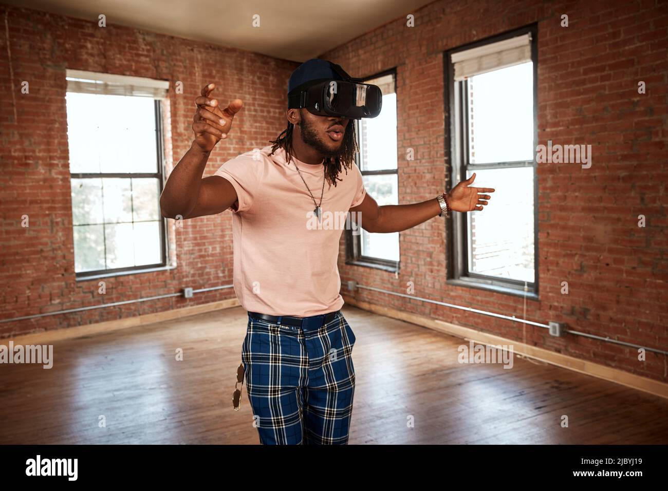 portrait of stylish young ethnic man wearing VR headset in empty loft space Stock Photo