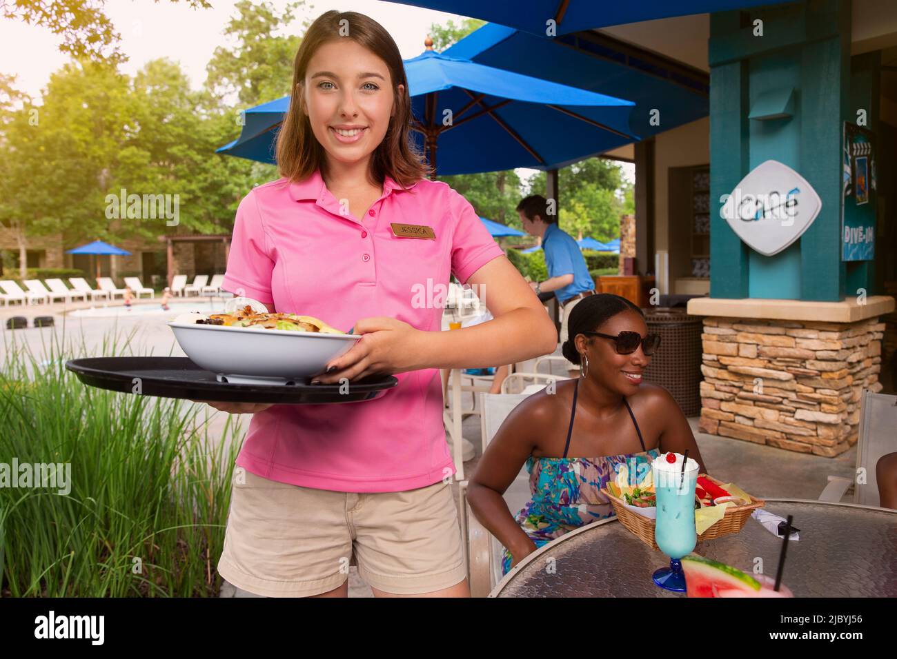 Portrait of a female waitress delivering salad to guest at poolside Hotel Cafe Stock Photo