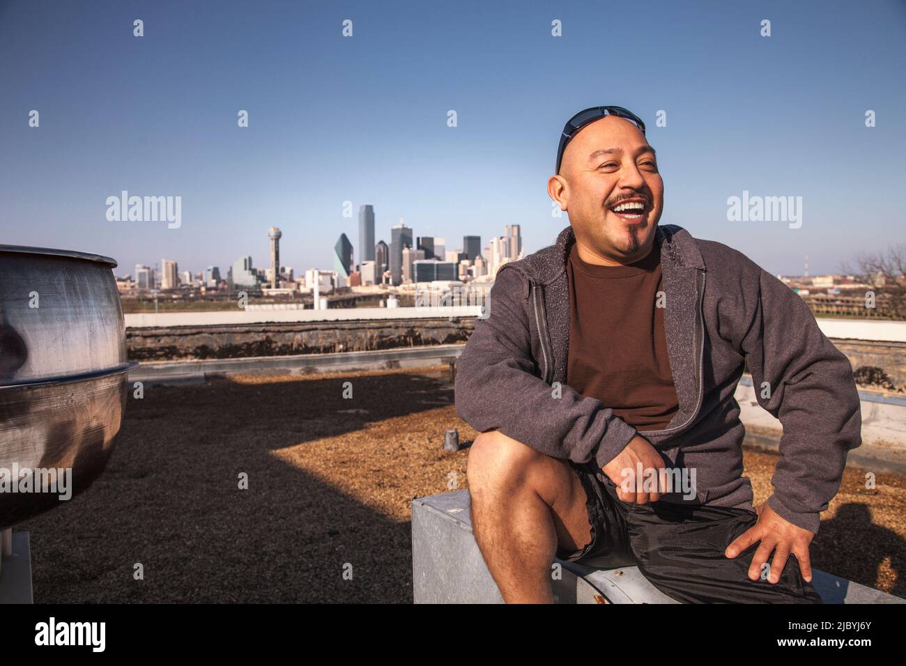 Laughing man sitting on rooftop Stock Photo
