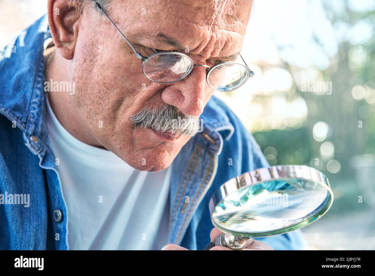 Older man using magnifying glass Stock Photo
