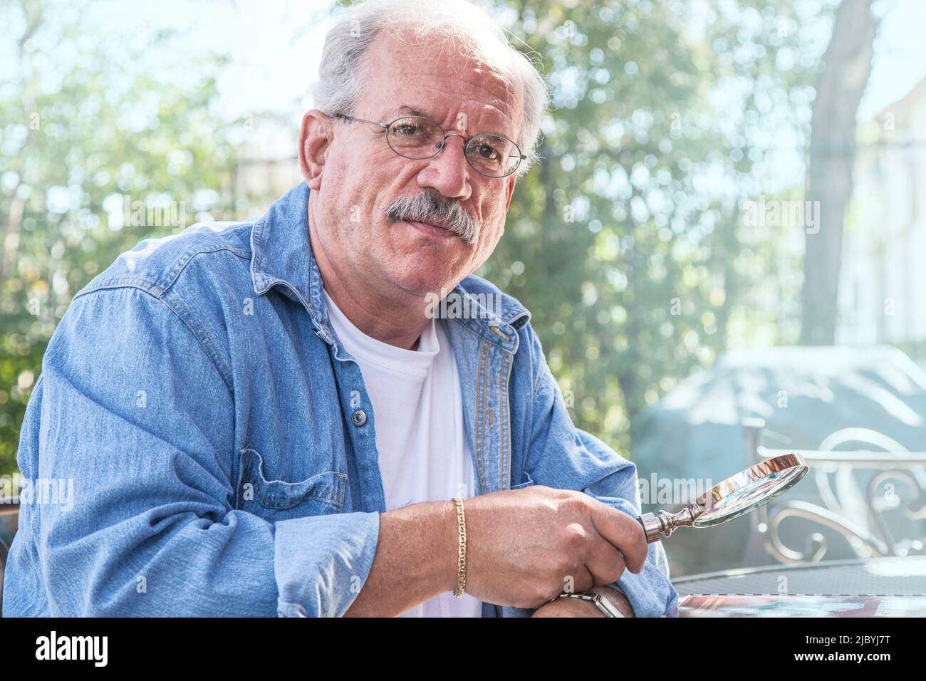 Serious older man holding magnifying glass Stock Photo