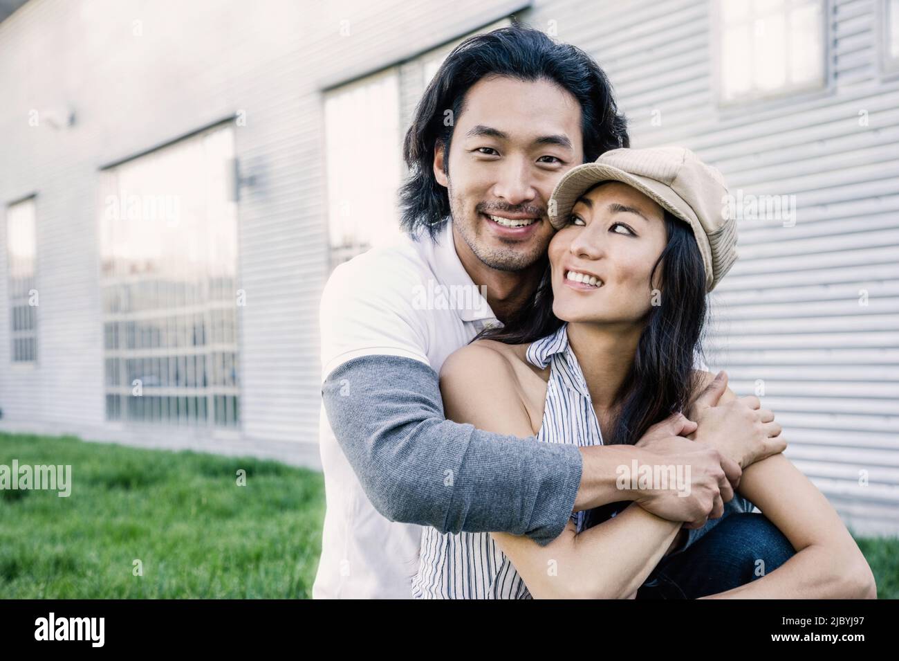 Korean couple hugging on lawn outside house Stock Photo