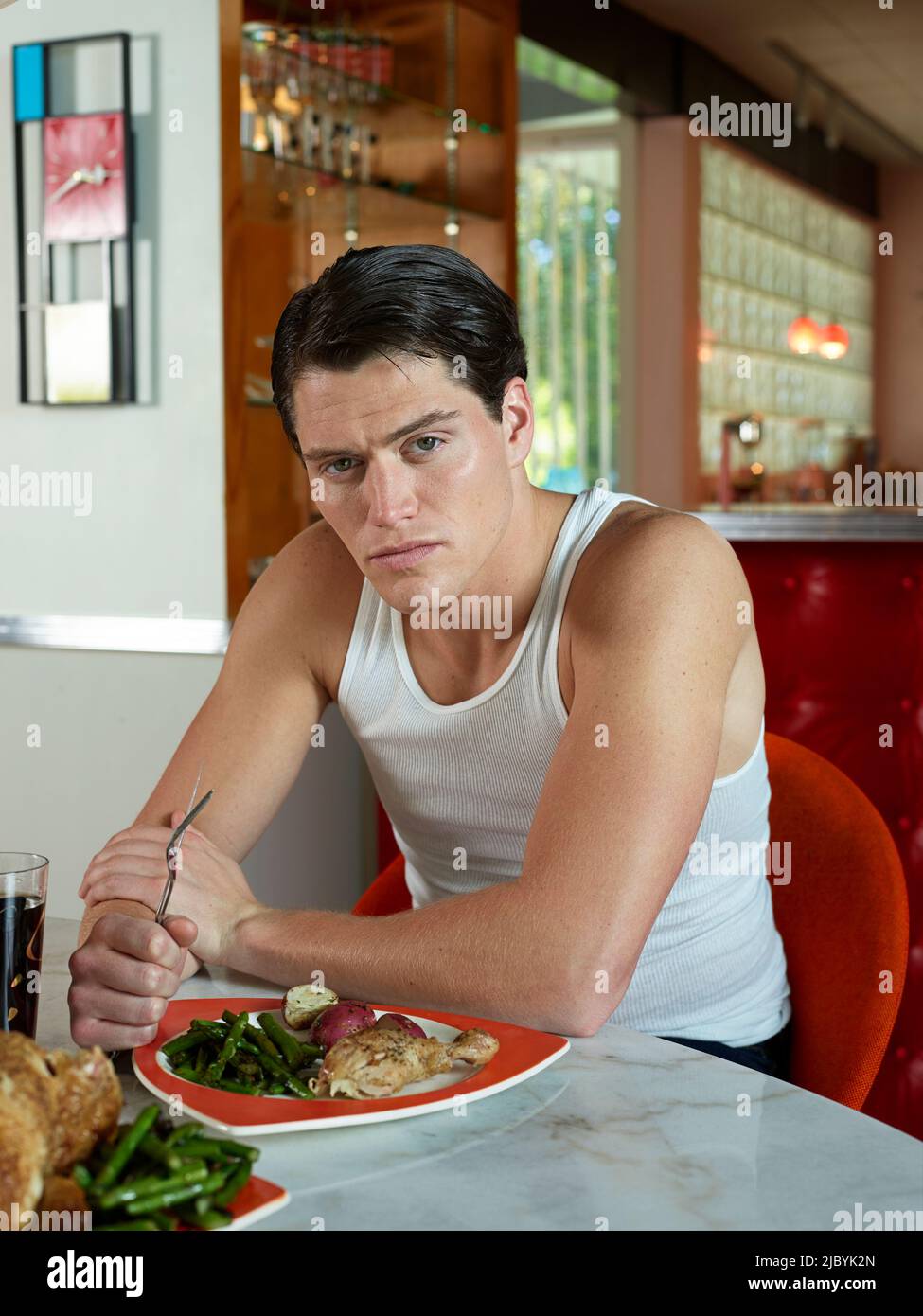 Portrait of a man sitting at a dining table in a mid-century modern home. Stock Photo
