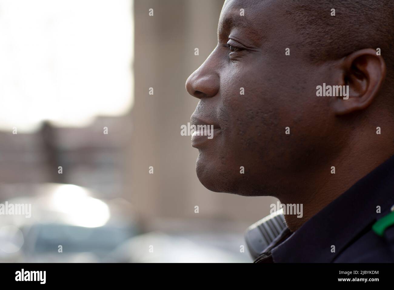 Close up profile Portrait of uniformed Police officer sitting outside looking off camera Stock Photo