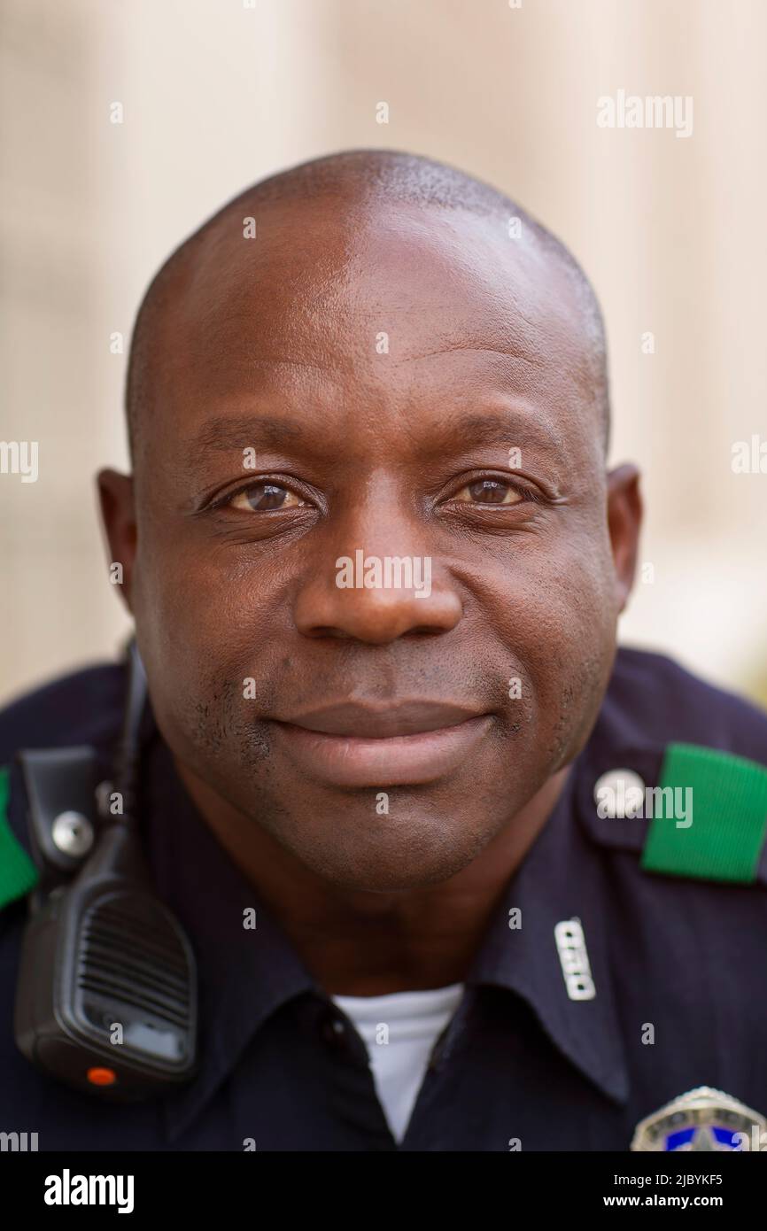Close up Portrait of uniformed Police officer sitting outside looking towards camera smiling Stock Photo