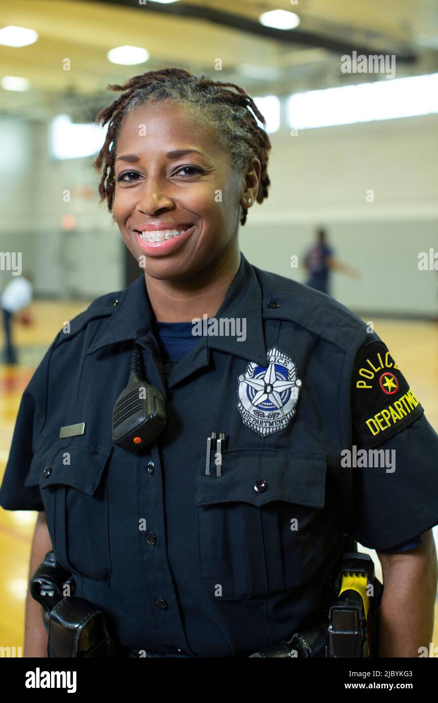 Portrait of Police woman standing in gymnasium looking towards camera smiling Stock Photo