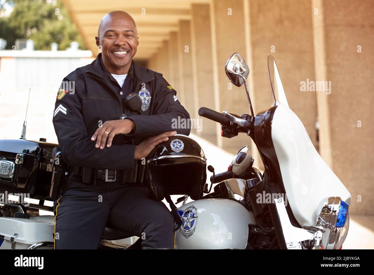 Portrait of Police officer sitting on his motorcycle outside looking towards camera smiling Stock Photo