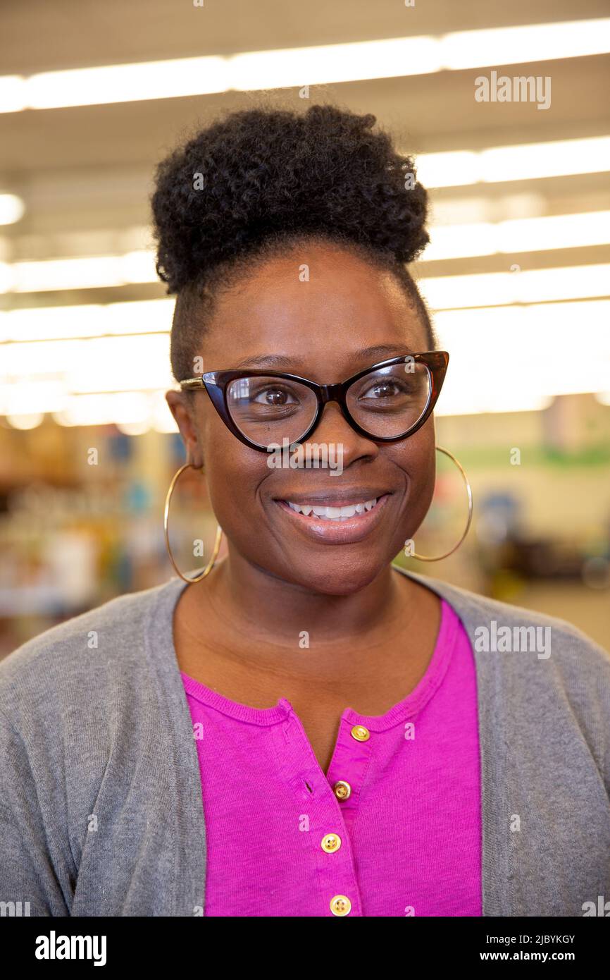 Portrait of smiling woman wearing retro glasses and large hoop ear rings, looking off camera smiling Stock Photo