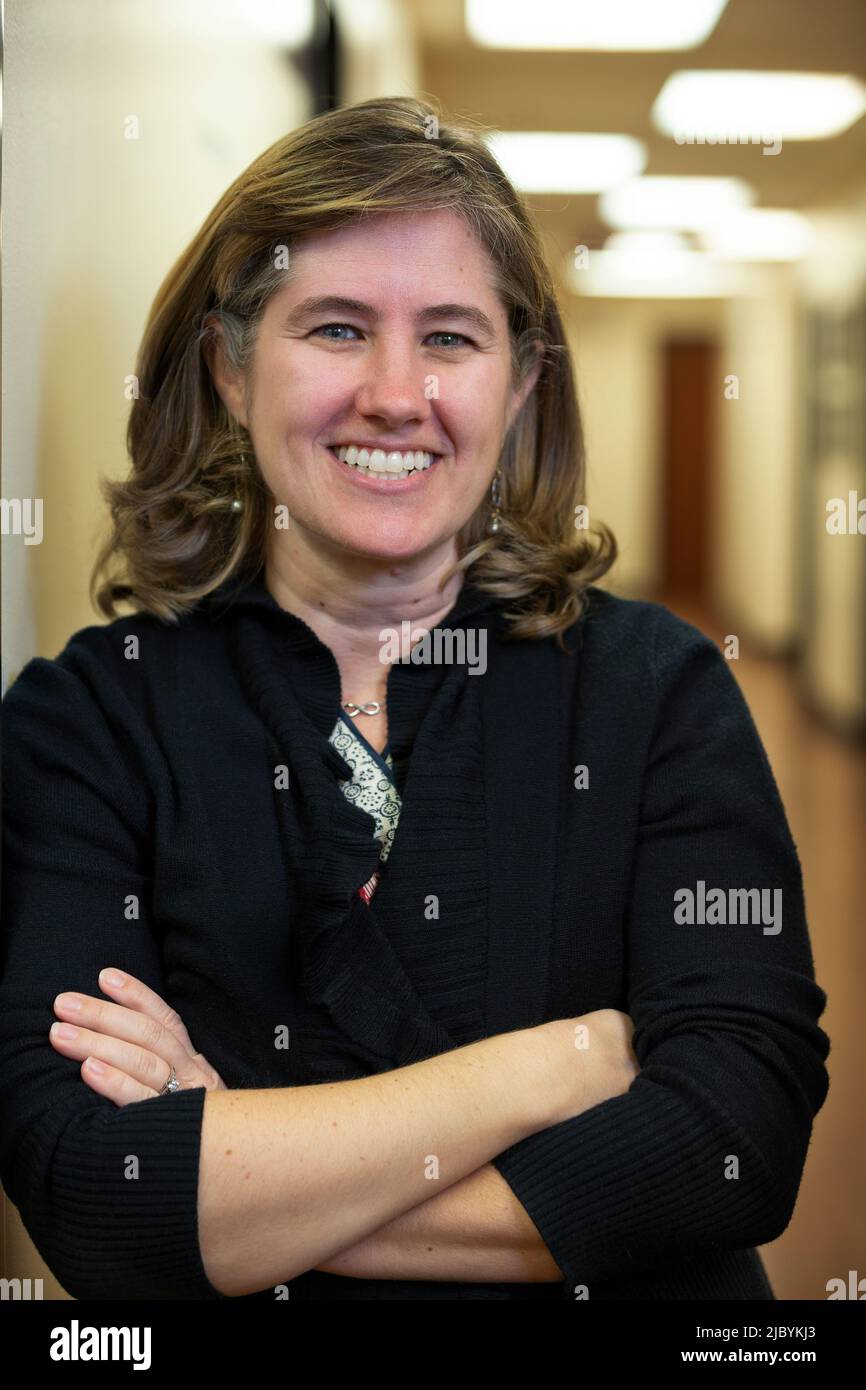 Portrait of middle aged woman with arms crossed smiling in hallway of office building Stock Photo