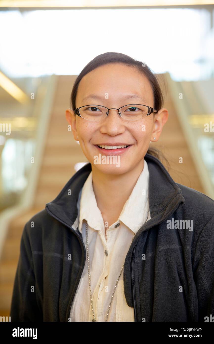 Portrait of young ethnic woman standing in lobby of building, smiling looking towards camera Stock Photo