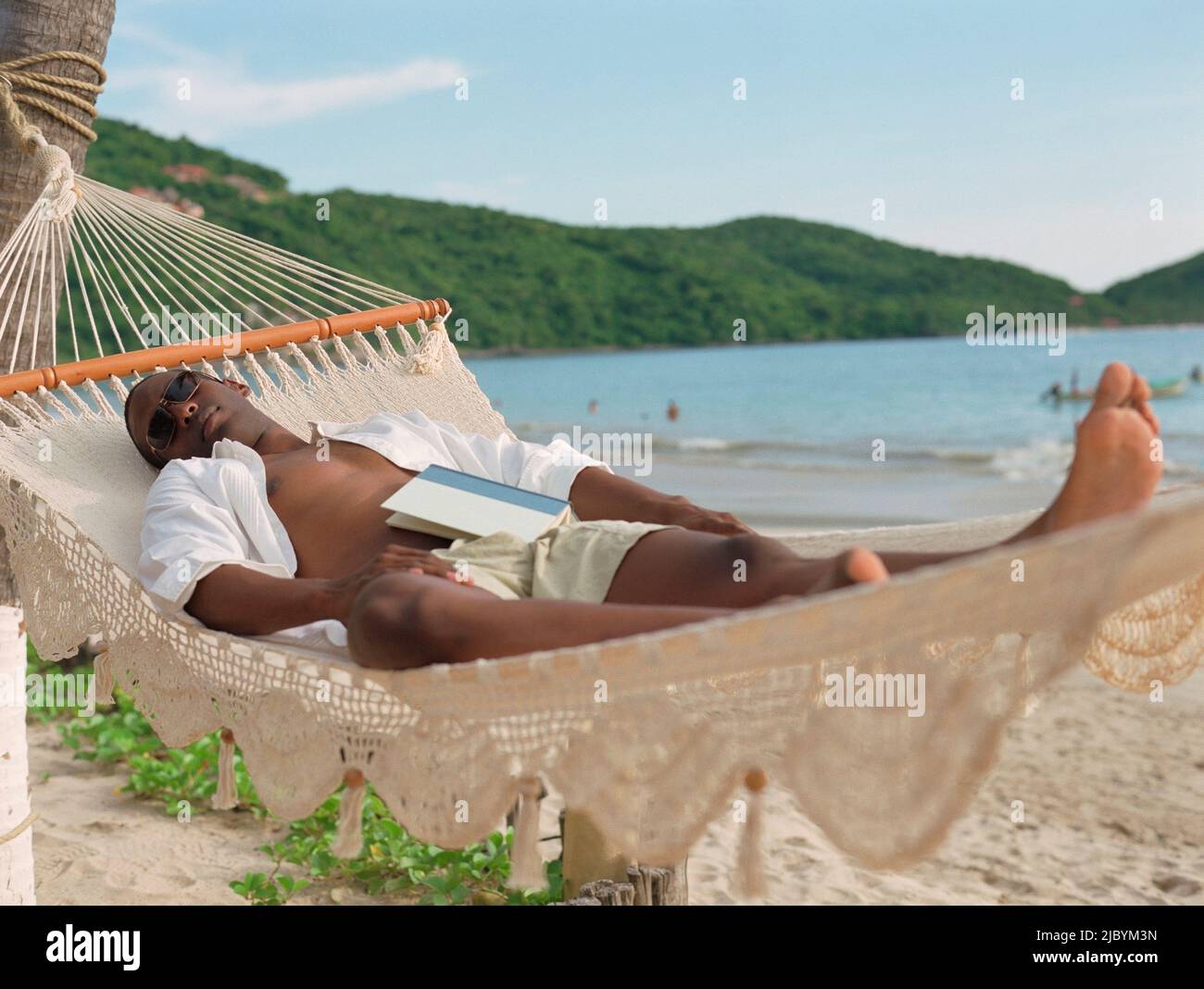 Hispanic man sleeping in hammock at beach Stock Photo