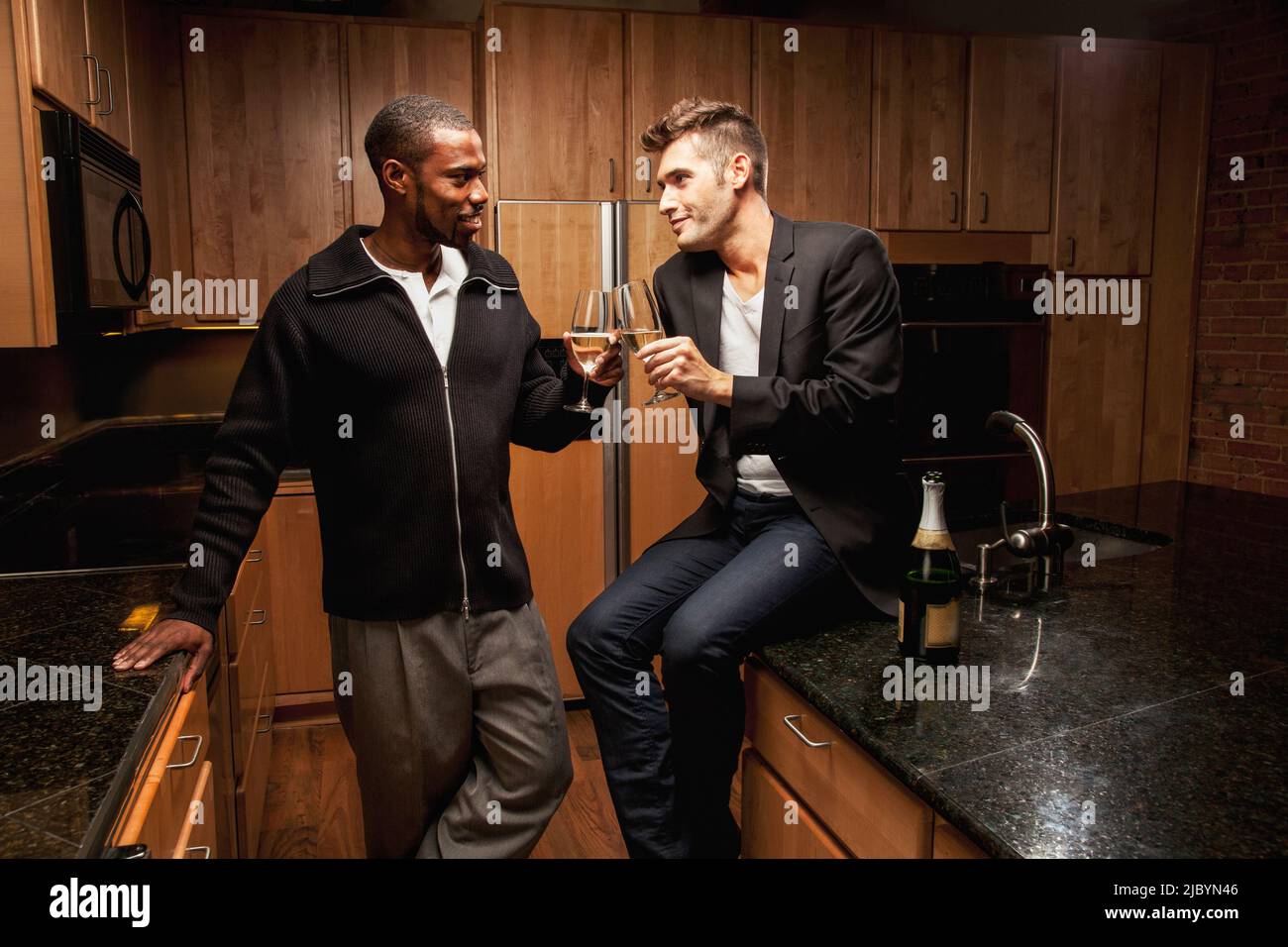 Gay couple drinking wine in kitchen Stock Photo