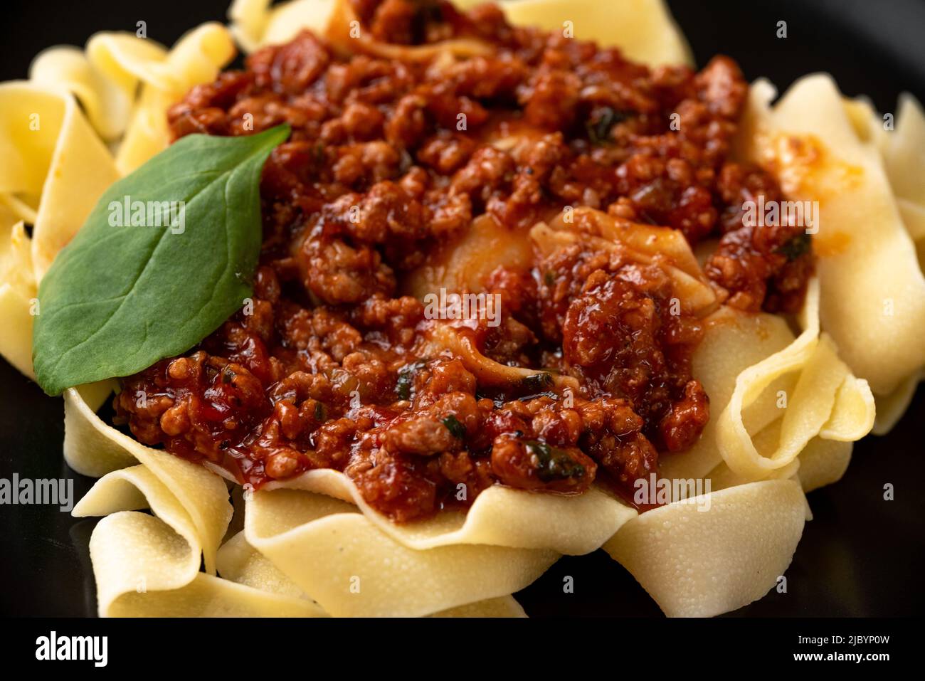 Pasta pappardelle with beef ragout sauce in black bowl. Grey background. Top view. Close up Stock Photo