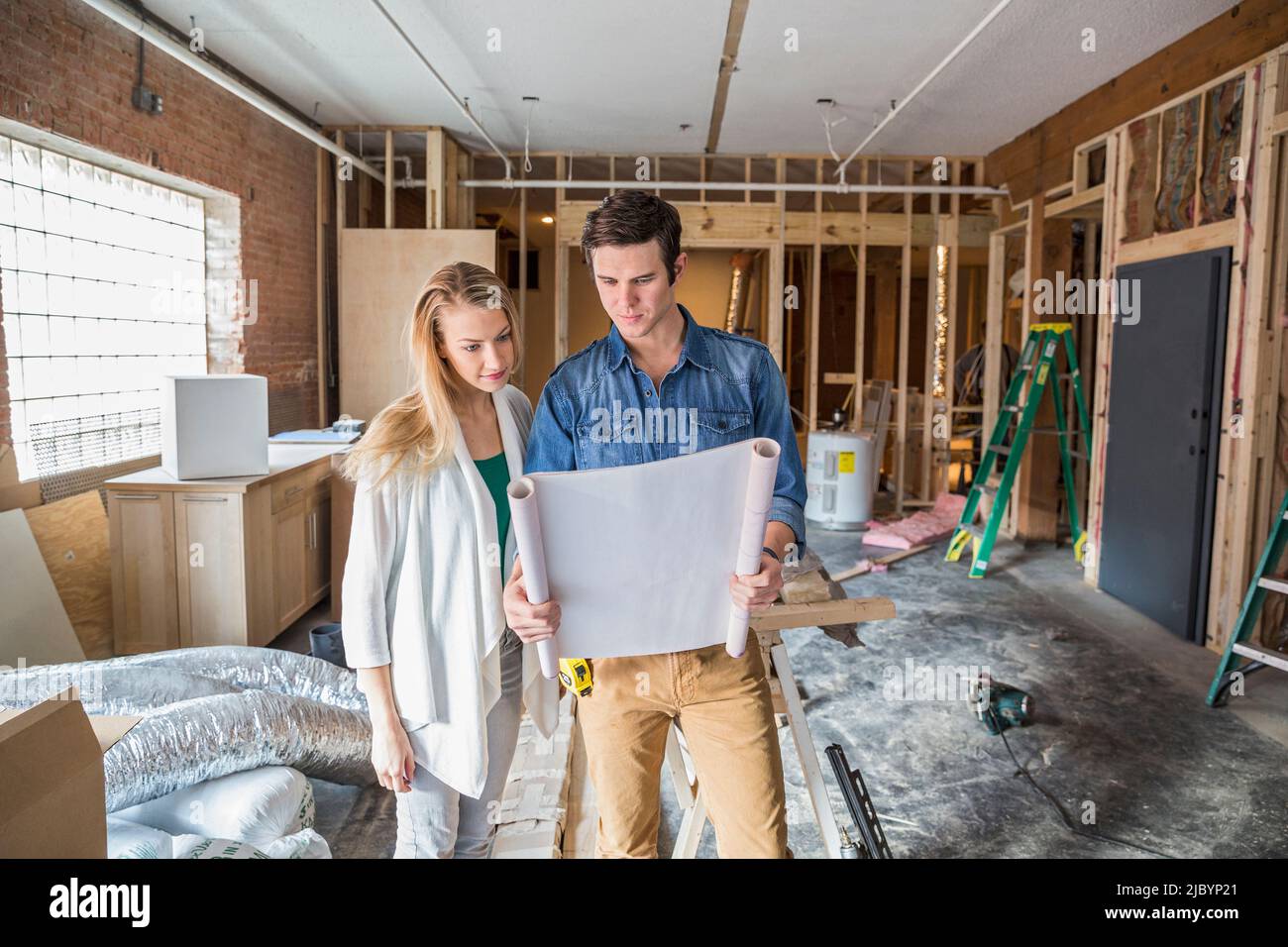 Caucasian couple reading blueprints at construction site Stock Photo