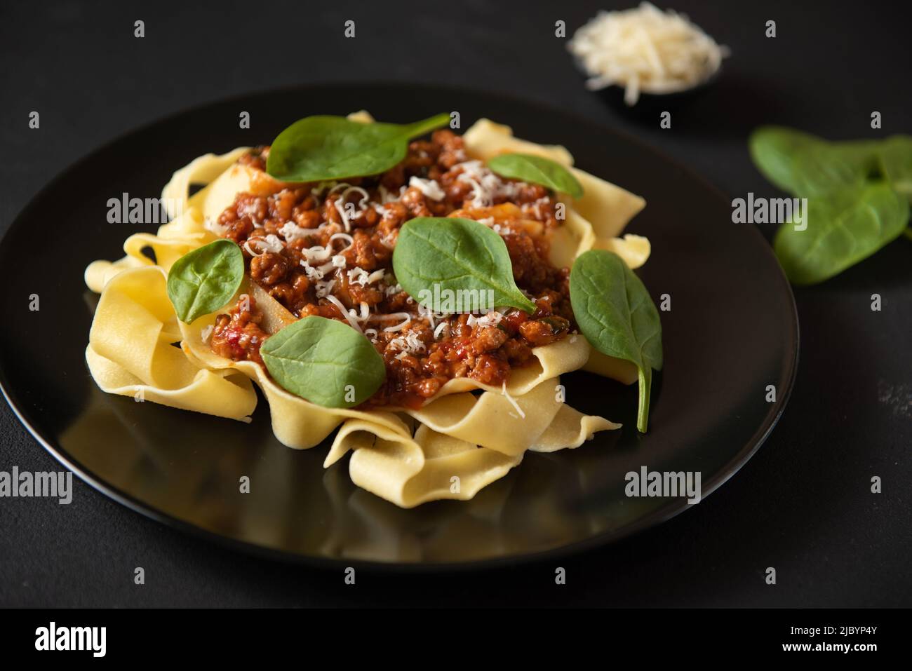 Traditional Italian pasta pappardelle with cheese and basil on a black plate on a dark background Stock Photo