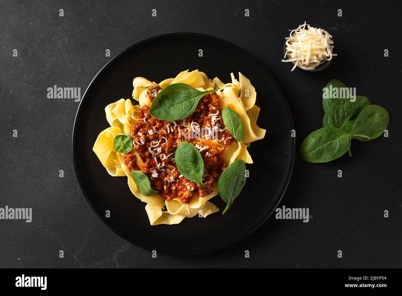 Traditional Italian pasta pappardelle with cheese and basil on a black plate on a dark background, top view Stock Photo