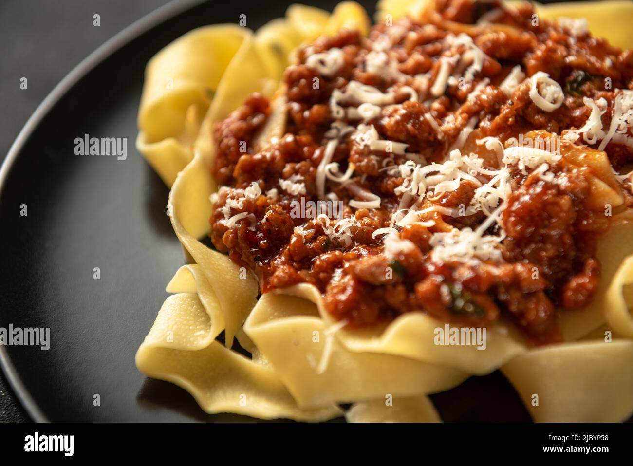 Pasta pappardelle with beef ragout sauce in black bowl. Grey background. Top view. Stock Photo