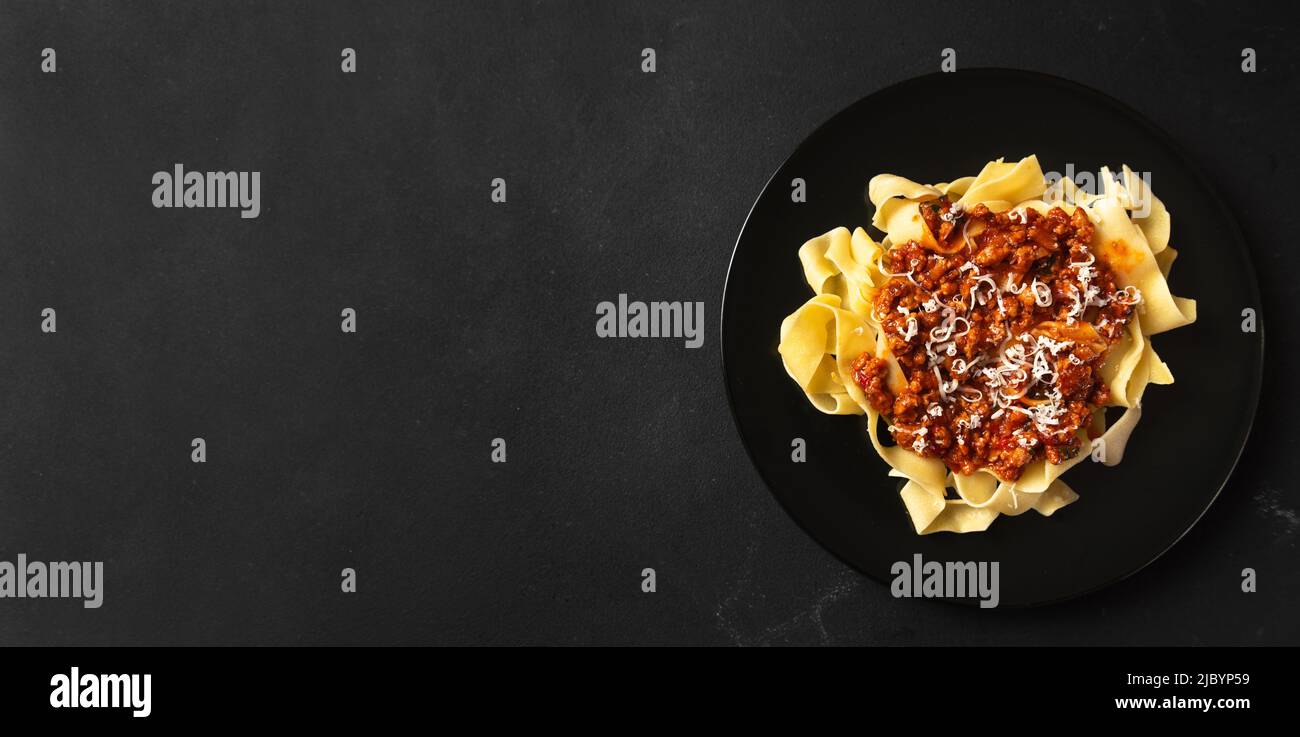 Pasta pappardelle with beef ragout sauce in black bowl. Grey background. Copy space. Stock Photo