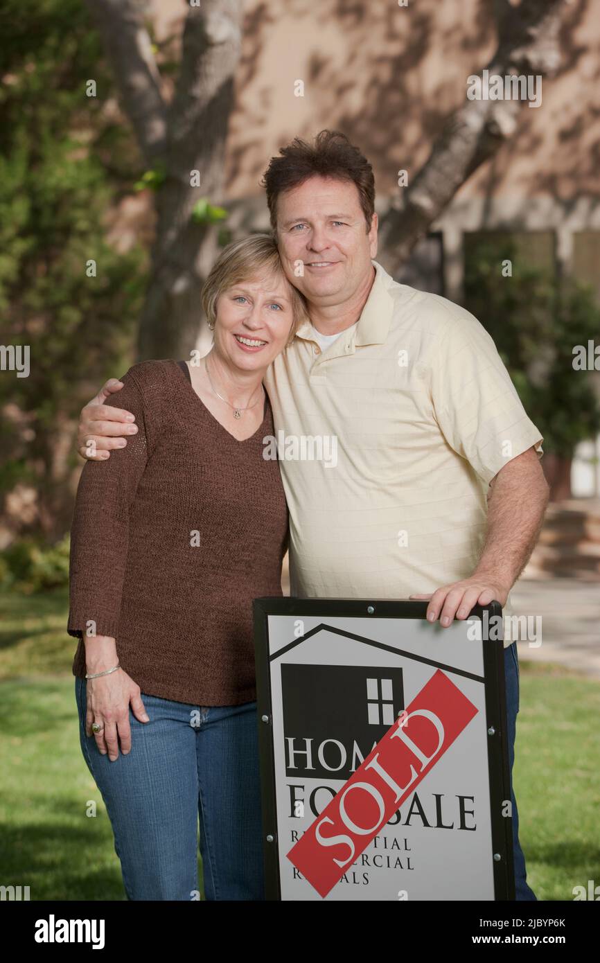 Couple standing in yard with sold sign Stock Photo - Alamy