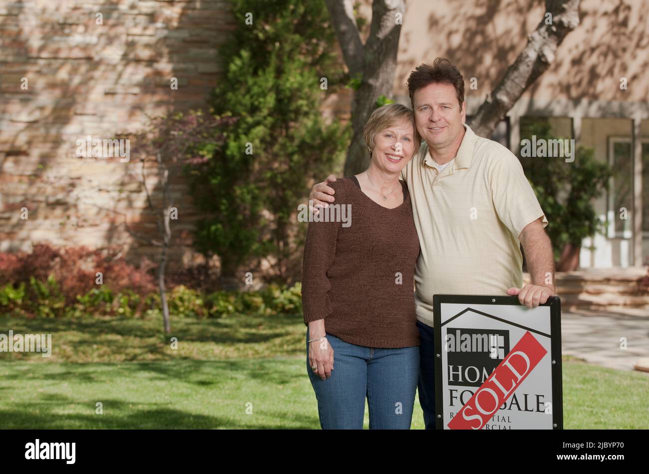 Couple standing in yard with sold sign Stock Photo - Alamy