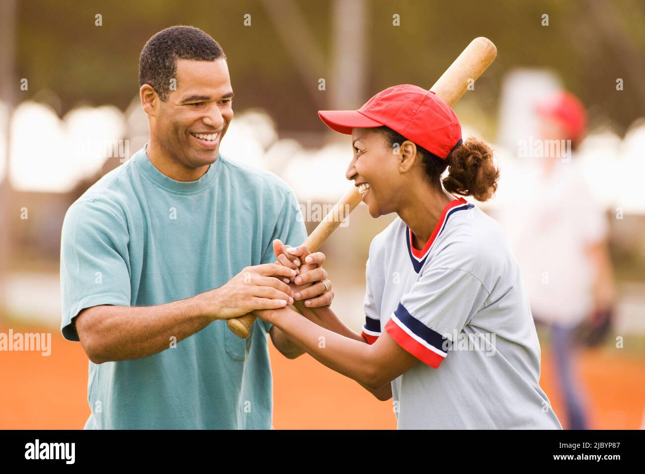 Man teaching girlfriend to play baseball Stock Photo
