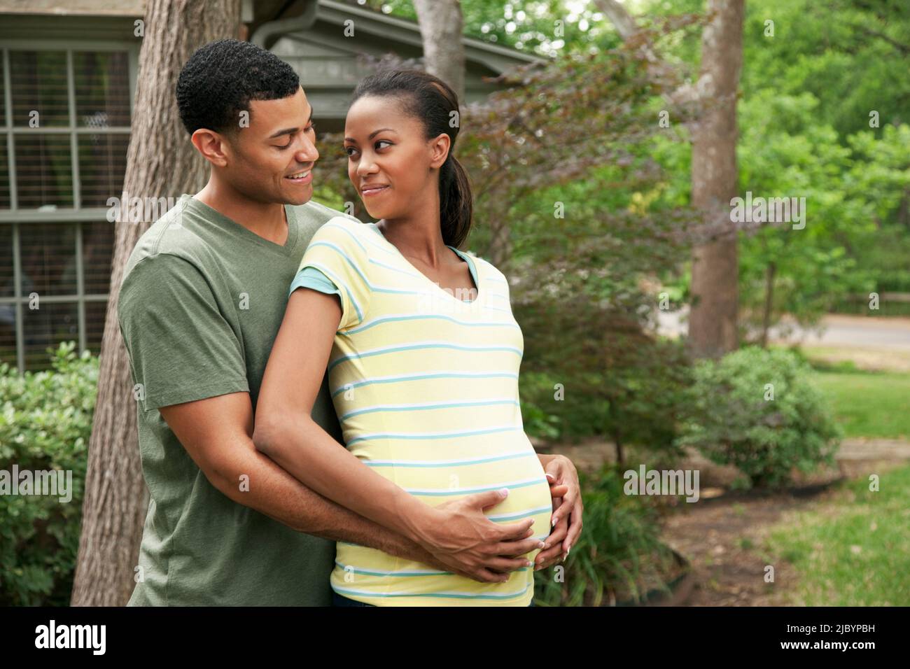 Man hugging pregnant wife in yard Stock Photo - Alamy