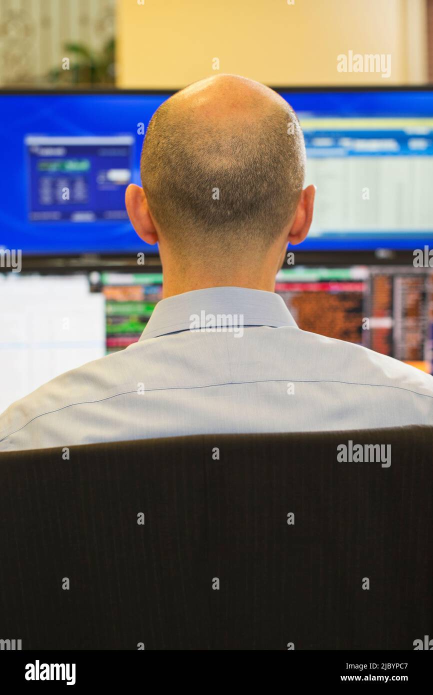 Rear view of trader using computer in office Stock Photo