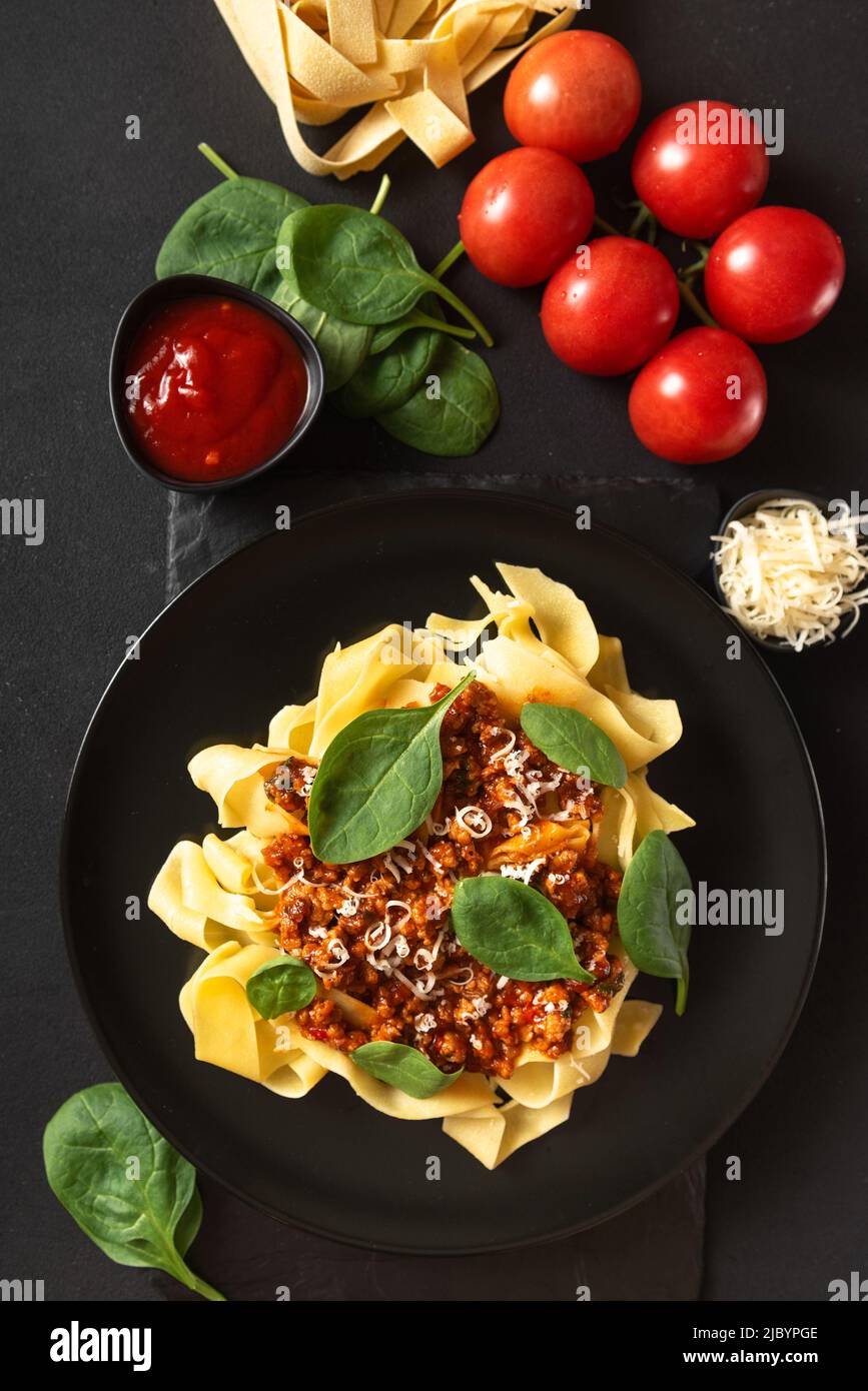Italian food on a gray background. Spaghetti tomato cheese and basil. View from above. Vertical frame Stock Photo