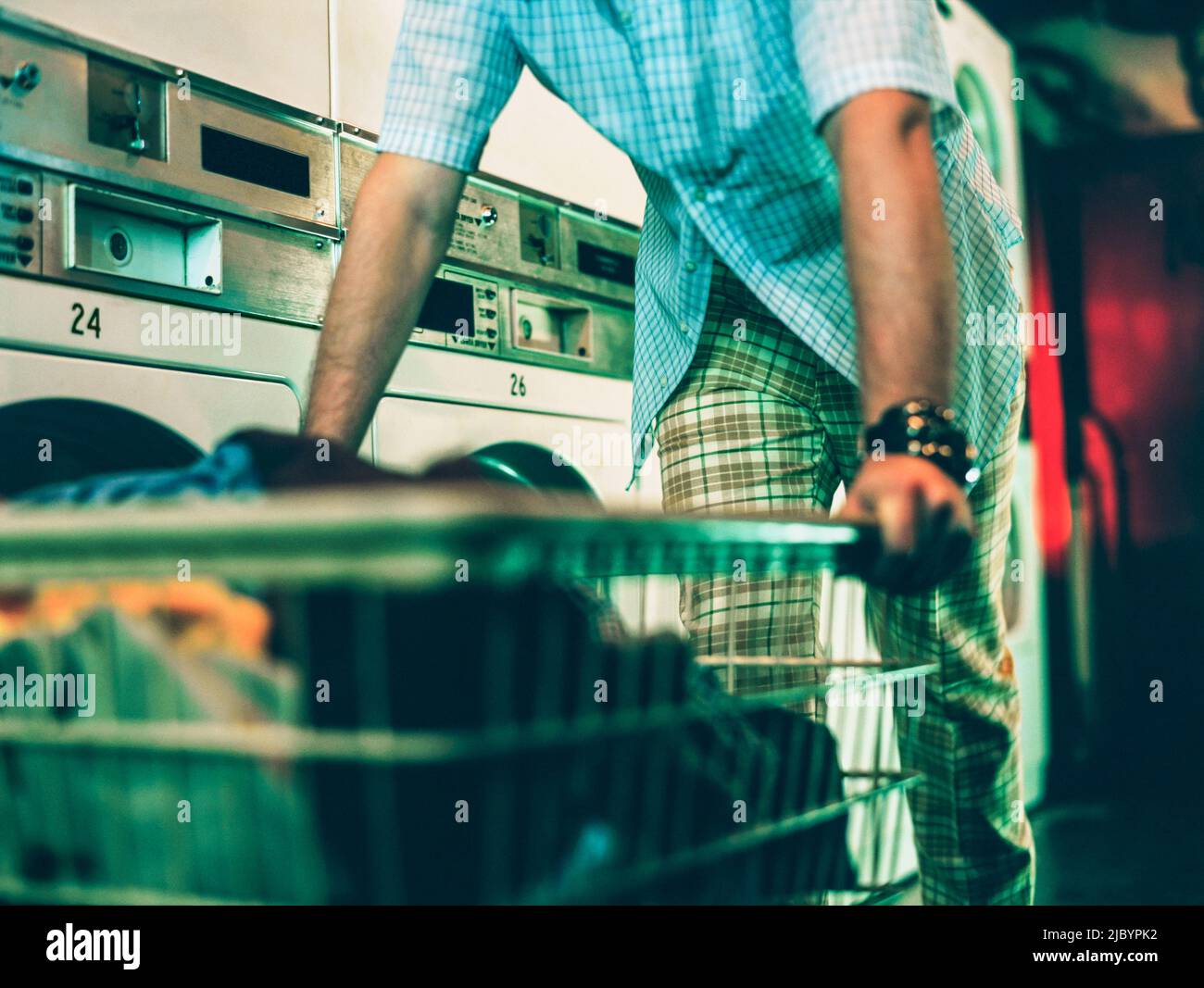 Man pushing laundry basket in laundromat Stock Photo Alamy