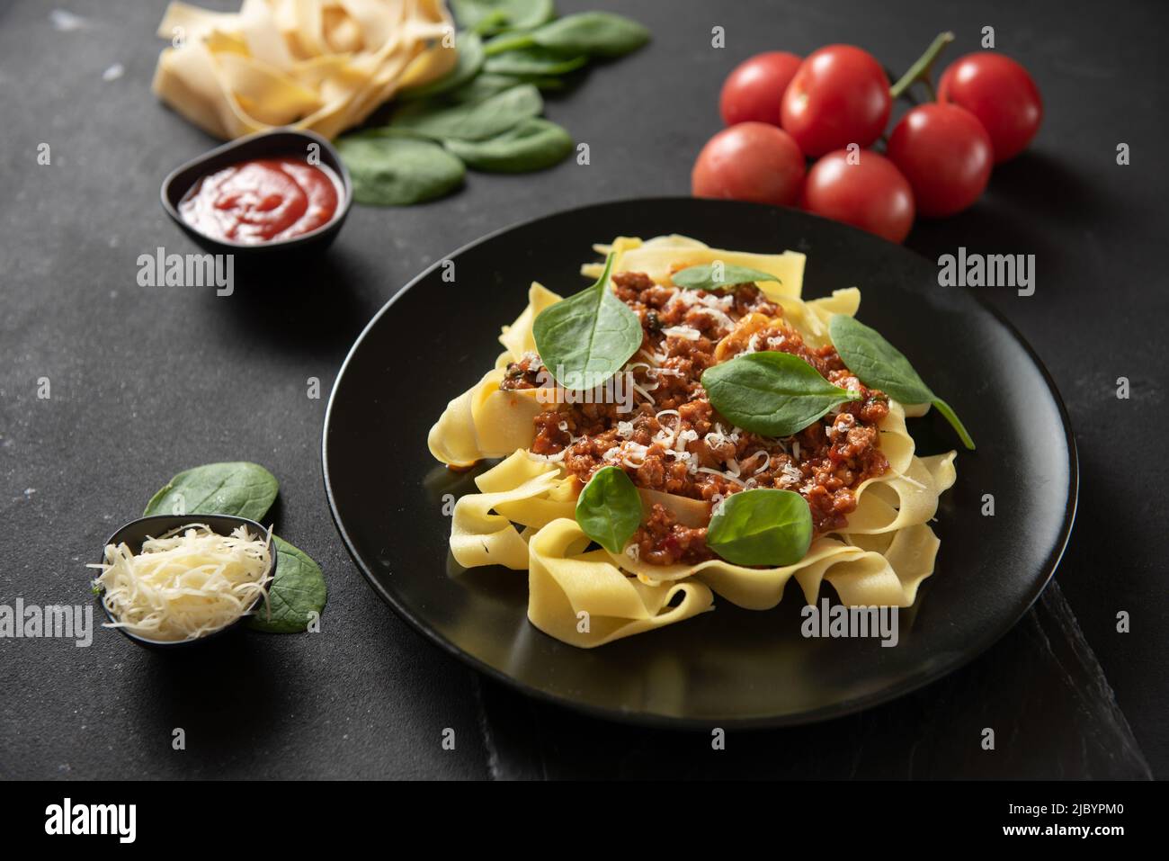 Pasta pappardelle with beef ragout sauce in black bowl. Grey background. Top view. Stock Photo