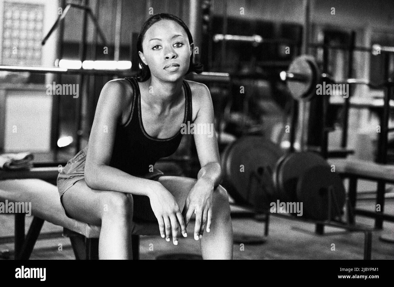 African woman sitting on weight bench Stock Photo