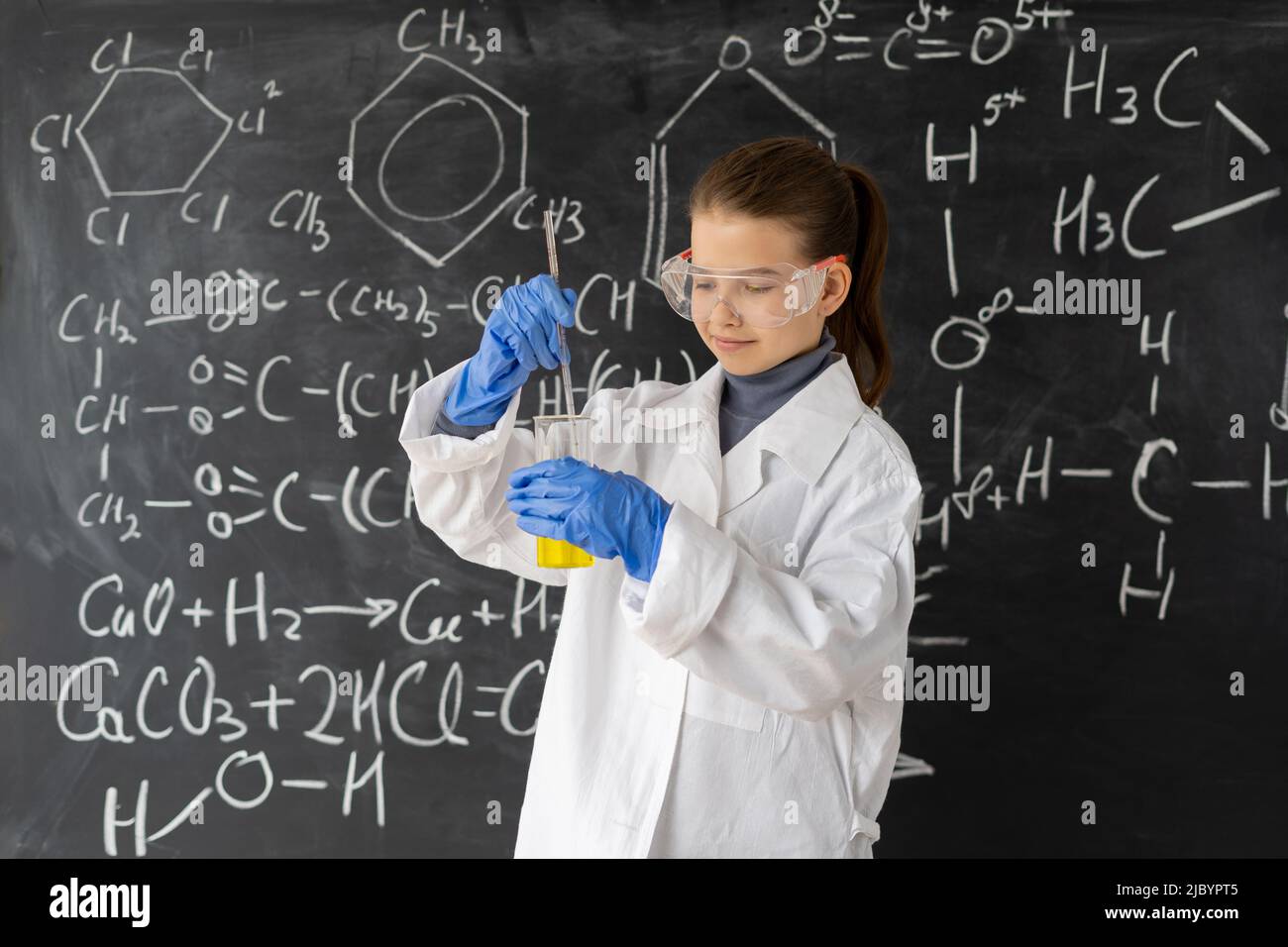 Little girl scientist examining flask with chemical reagent. Schoolgirl making experiment in chemistry class. children working in a chemistry lesson Stock Photo