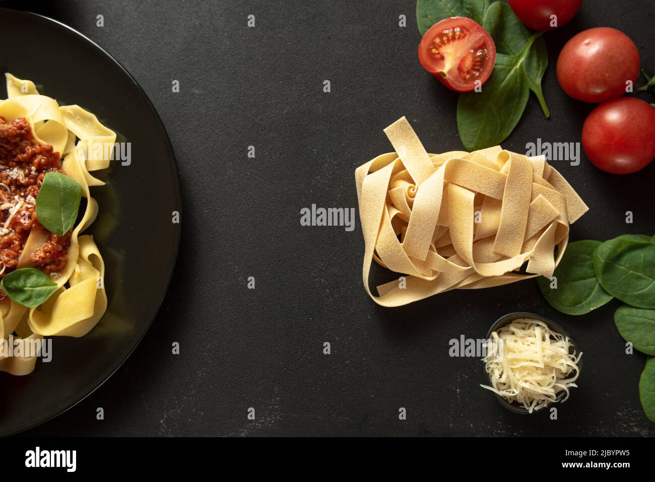 Pasta raw pappardelle on a dark background with ingredients for cooking