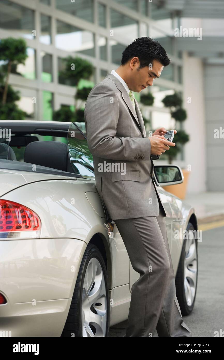 Chinese businessman text messaging on cell phone Stock Photo