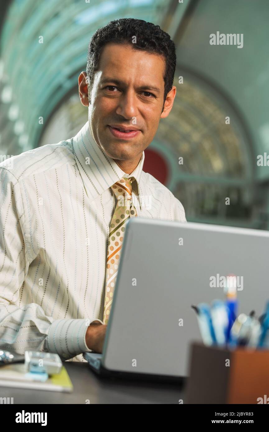 Hispanic businessman typing on laptop Stock Photo