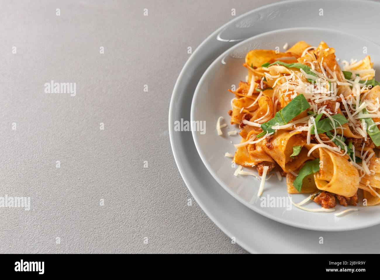 Pasta pappardelle with beef ragout sauce in black bowl. Grey background. Top view. Stock Photo