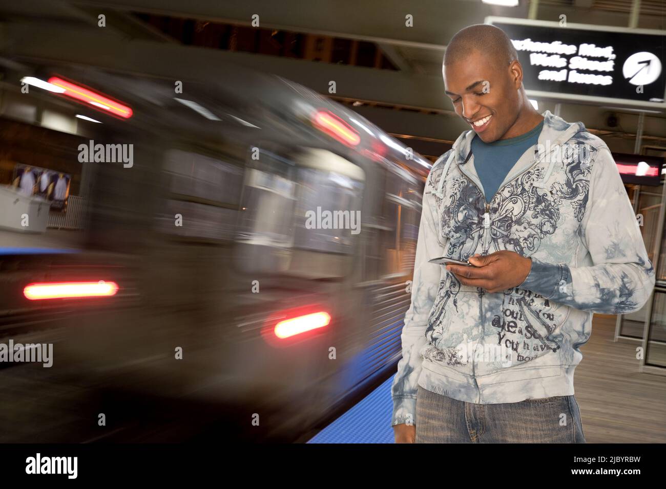 Black man text messaging on cell phone in subway Stock Photo