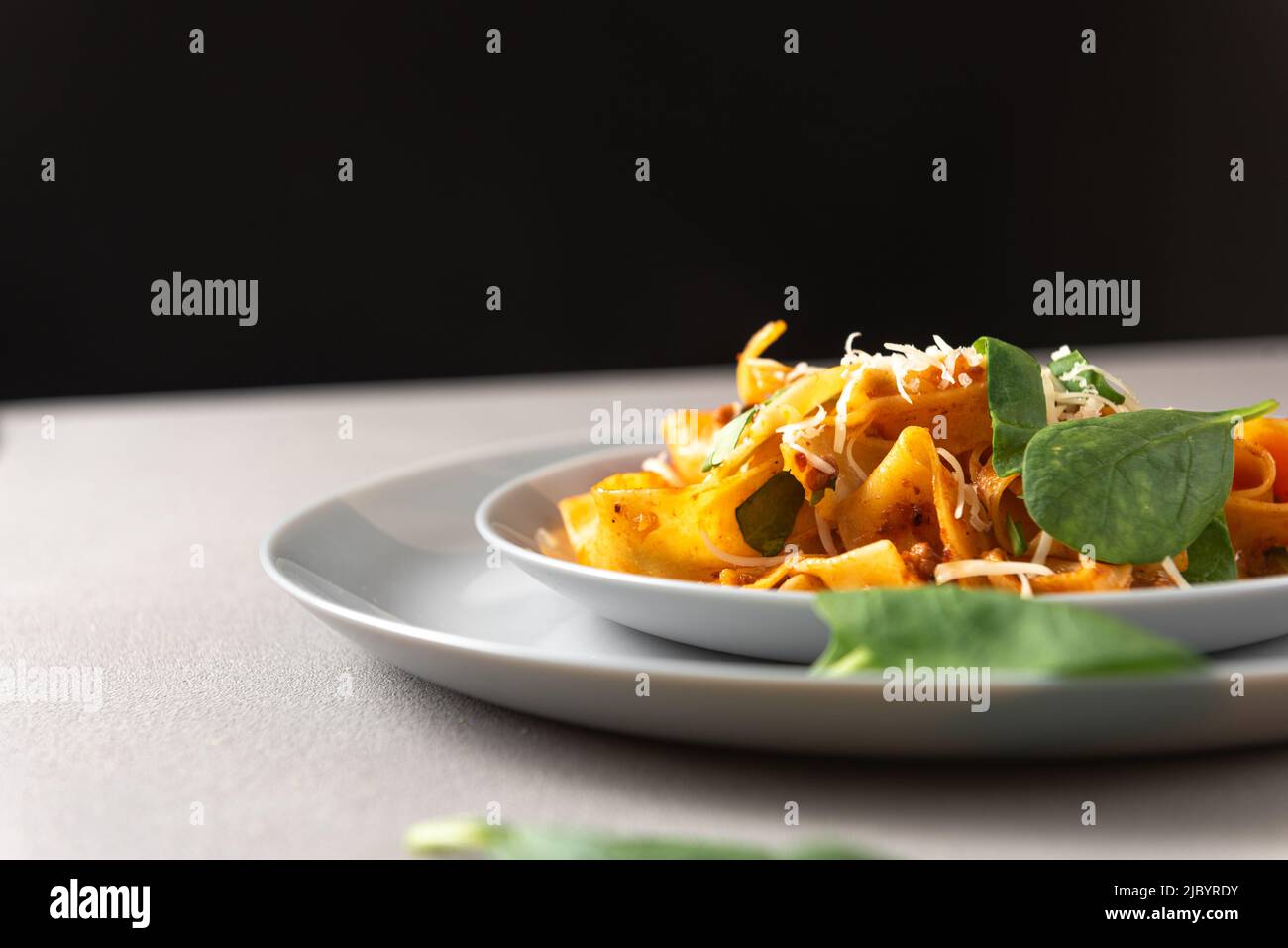 Pasta pappardelle with beef ragout sauce in grey bowl. Grey background Stock Photo