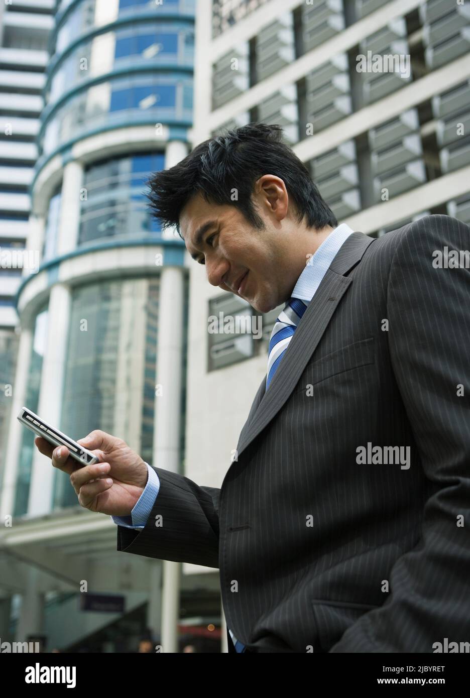 Chinese businessman text messaging on cell phone Stock Photo