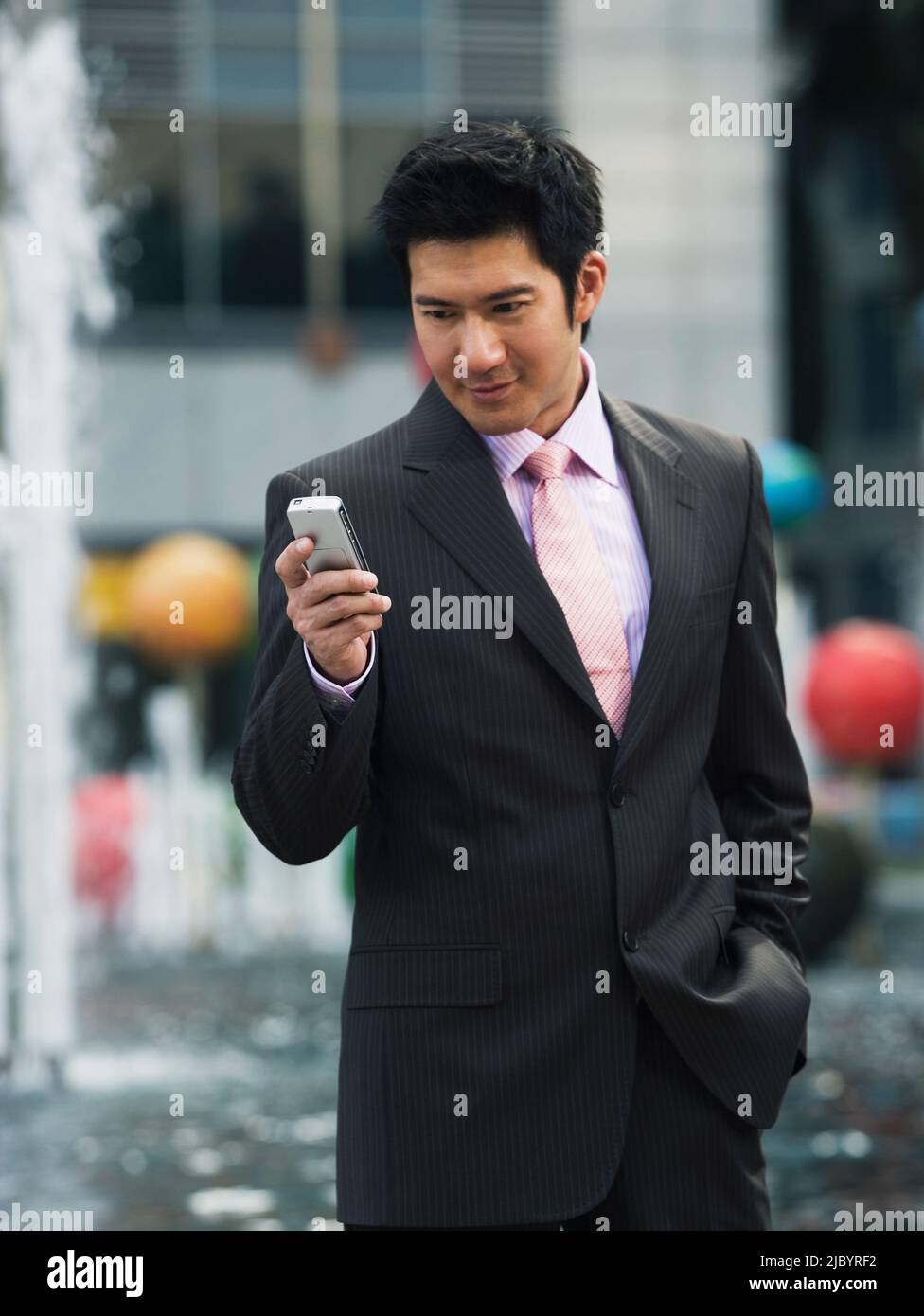 Chinese businessman text messaging on cell phone Stock Photo