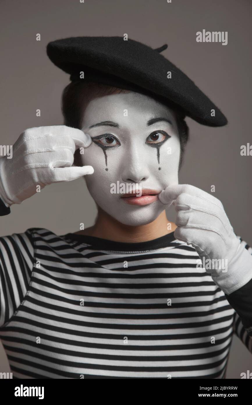 Woman in mime costume stretching her face Stock Photo