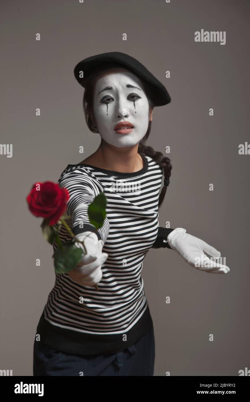 Woman in mime costume holding out rose Stock Photo - Alamy