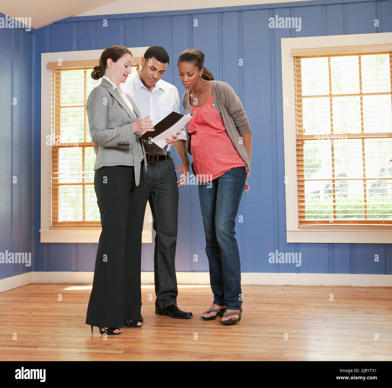 Couple talking with realtor in empty house Stock Photo