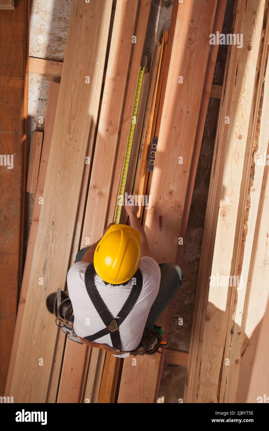 Mixed race construction worker measuring lumber Stock Photo
