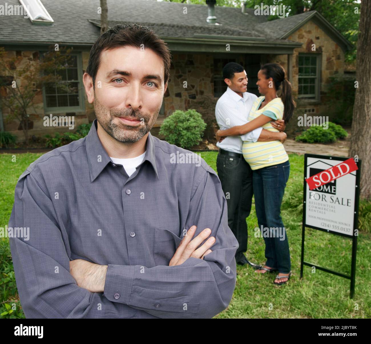 Realtor and couple standing in yard with sold sign Stock Photo - Alamy