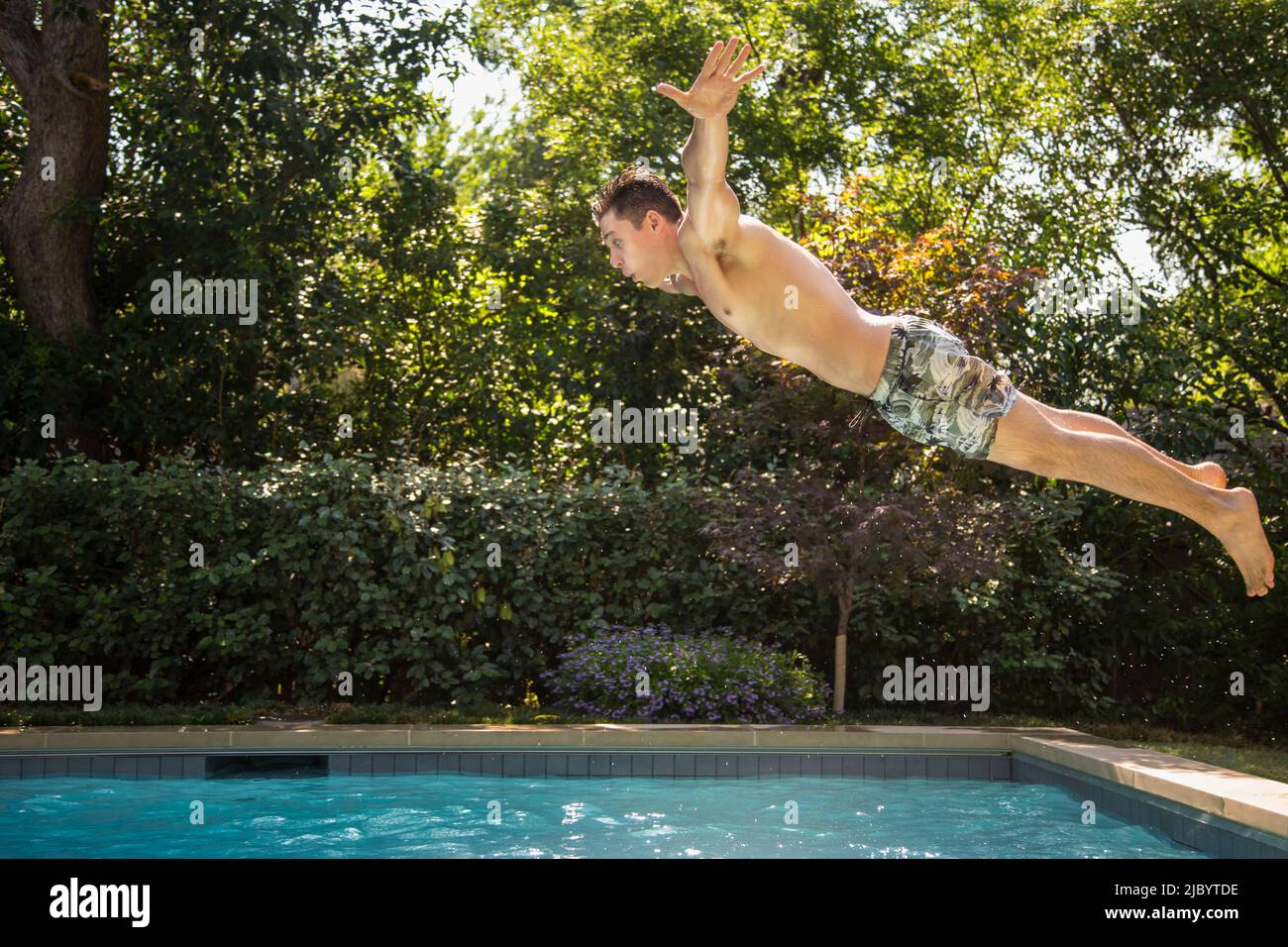 Man jumping into swimming pool Stock Photo
