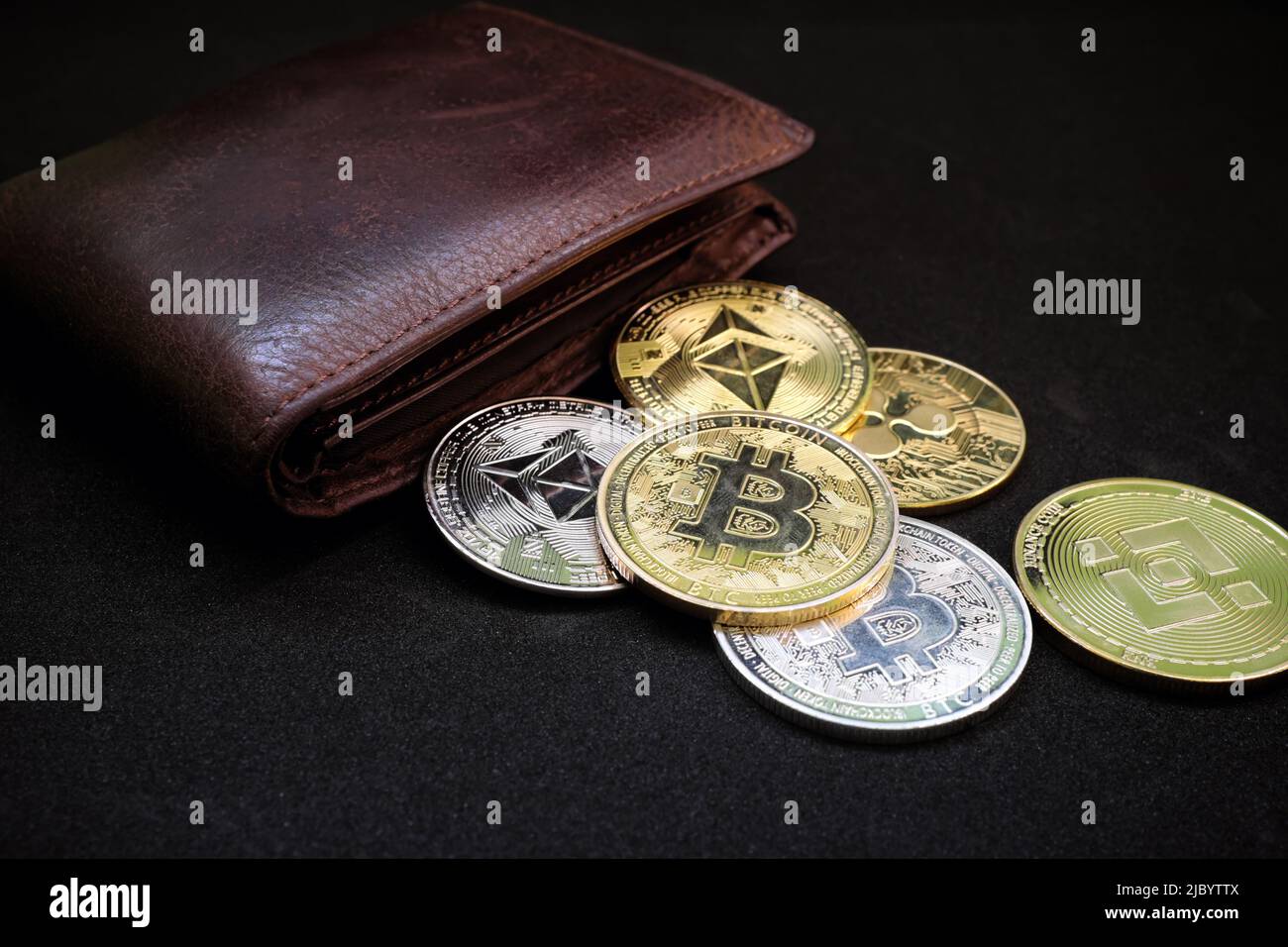 Cryptocurrency wallet, saving and investment concept. Wallet with different crypto coins like bitcoin and ethereum on black background. Stock Photo
