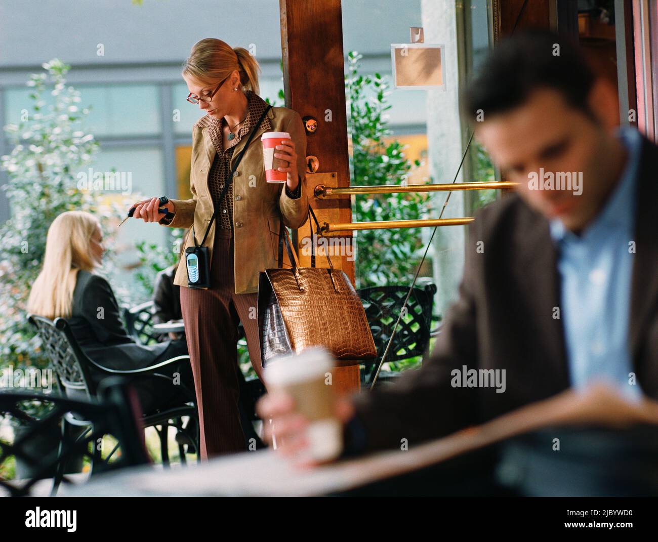 Businesswoman holding to go coffee in cafe Stock Photo