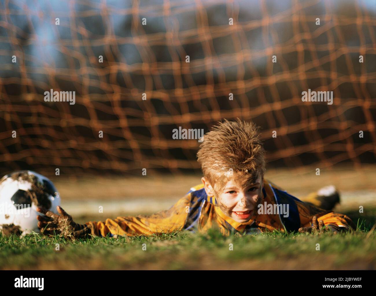 Boy covered in mud with soccer ball Stock Photo Alamy