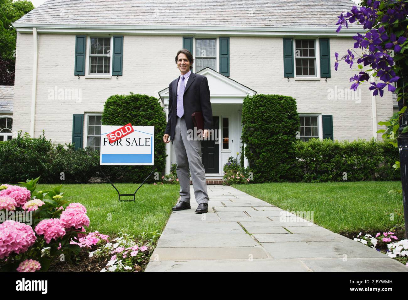 Male real estate agent and Sold sign in front of house Stock Photo - Alamy